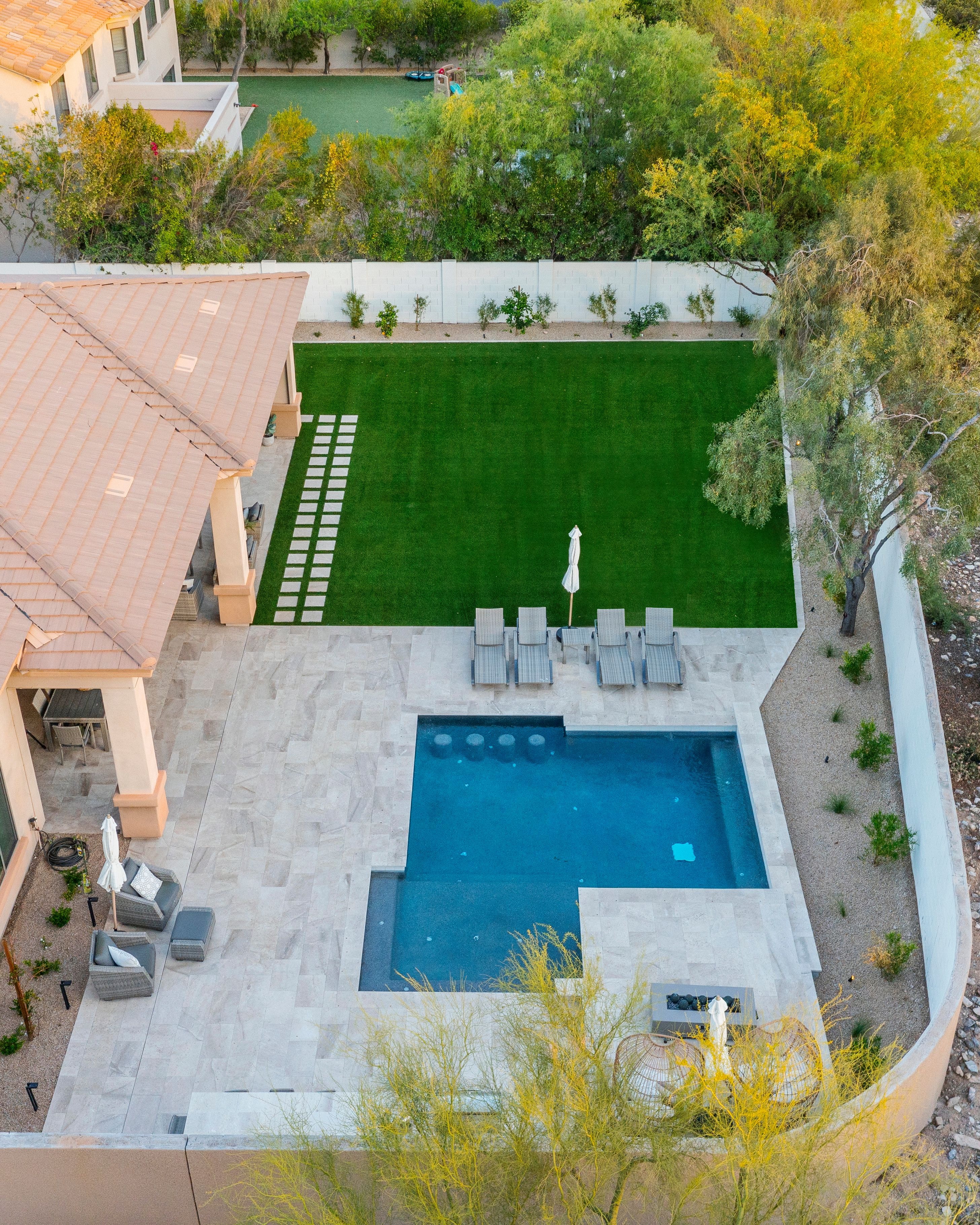 Full backyard transformation with dark-bottom pool, water features, turf, and outdoor kitchen at sunset