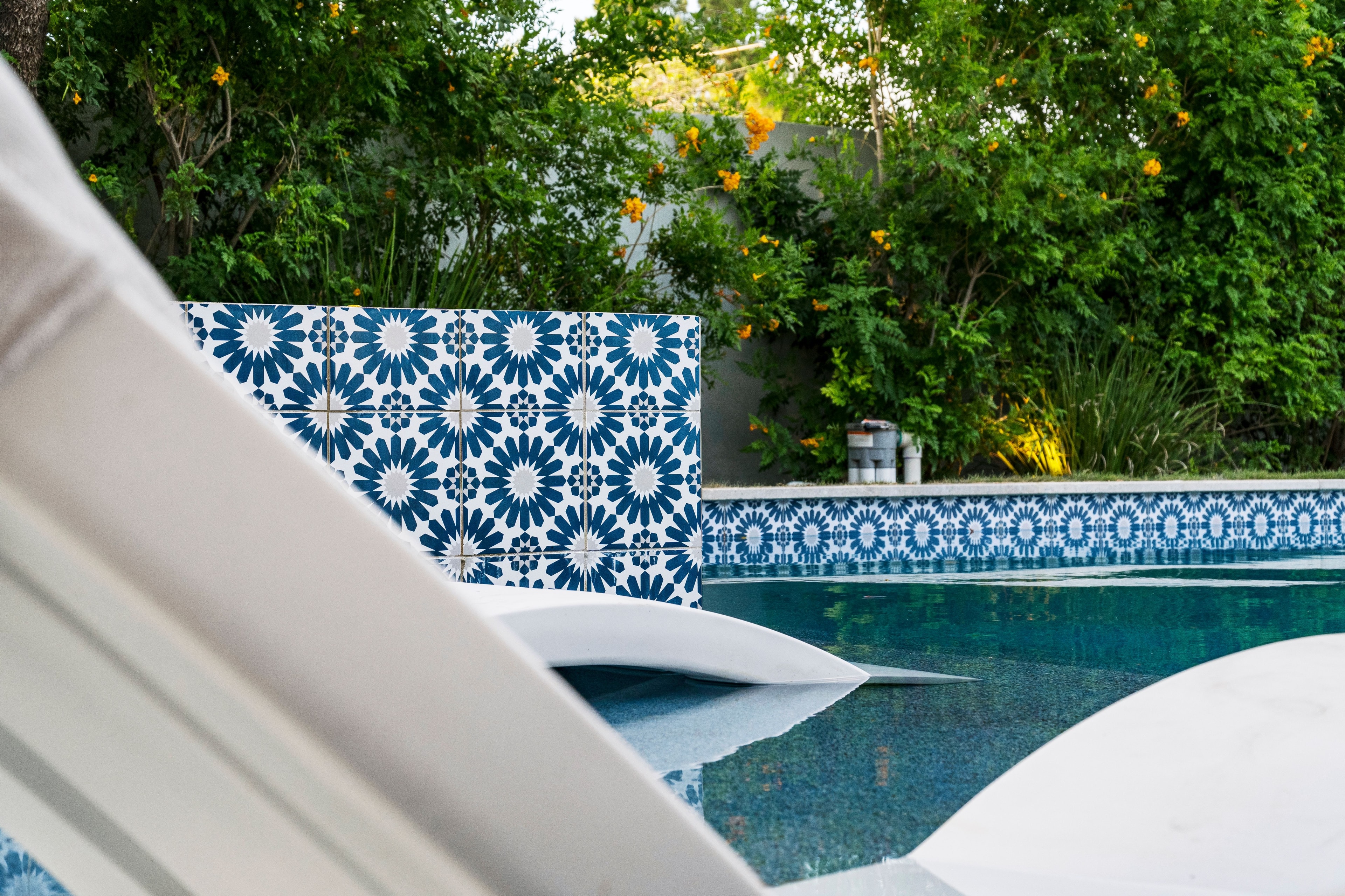 Poolside lounge chairs with bold blue and white Moroccan tile feature wall